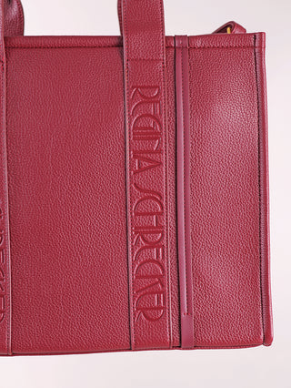 Regina Schrecker Shopper bordeaux aus rotem genarbtem Leder, zeigt zwei vertikale Griffe mit geprägtem Logo. Strukturierte, rechteckige Form mit sichtbaren Nähten, ideal für stilvolle Aufbewahrung.