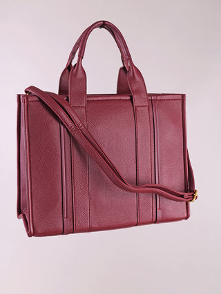 Regina Schrecker Shopper bordeaux: Eine strukturierte Tote-Handtasche aus burgunderfarbenem Polyurethan mit zwei oberen Henkeln, einem verstellbaren Schulterriemen und vertikalen Panelnähten an den Seiten.