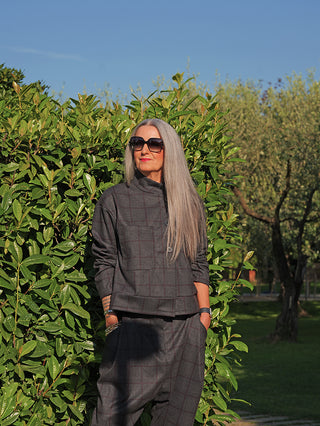 Ältere Frau im Garten trägt die OFF#DLY Jacke Adira grey/red, eine graue, karierte Jacke mit Stehkragen und lockerer Passform, kombiniert mit passender Hose, eleganter und moderner Look.