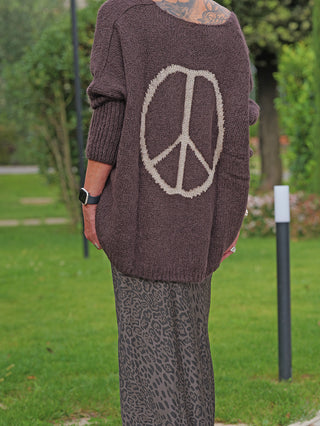Person von hinten in einem braunen OFF#DLY Pulli Selma mit großem Peace-Symbol am Rücken, kombiniert mit einem langen Leopard-Rock.