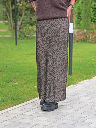 Person trägt den OFF#DLY Rock Gina braun/leo mit modernem Animal-Print, kombiniert mit schwarzen Plateauschuhen auf einem Gehweg. Der Rock fällt fließend und endet knapp über den Schuhen.