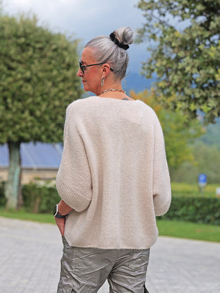 Frau von hinten mit OFF#DLY Cardigan Safira stone, weicher, locker geschnittener Strickpullover mit Dreiviertelärmeln und V-Ausschnitt, getragen über glänzenden Cargo-Hosen.