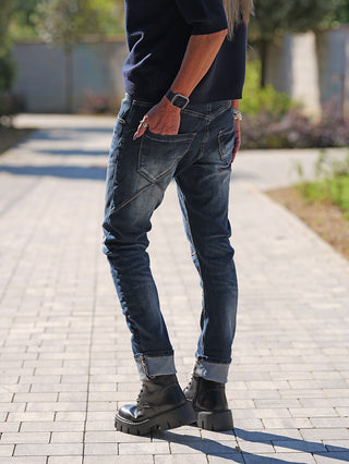 OFF#DLY Denim Life Dark Blue: Slim-Fit Jeans mit umgeschlagenem Saum, getragen mit schwarzen Schnürstiefeln. Kombiniert urbanen Stil und Komfort mit auffälligen Details und Stretchmaterial für Bewegungsfreiheit.