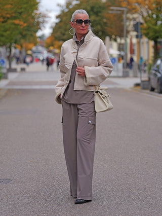 Penn&Ink Trousers taupe, weite Cargo-Hose mit großen Seitentaschen und elastischem Bund, getragen von älterer Frau in urbaner Herbstszene, kombiniert mit heller Jacke und strukturierter Handtasche.