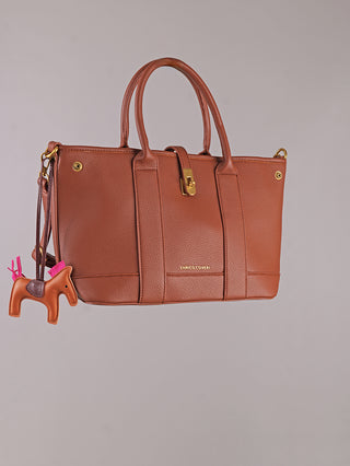 Enrico Coveri Tote Bag cognac aus Polyurethan mit goldener Hardware, zwei Henkeln und Frontverschluss. Verziert mit einem Pferdeanhänger mit pinkem Mähnendetail. Größe: 50 x 40 x 15 cm.