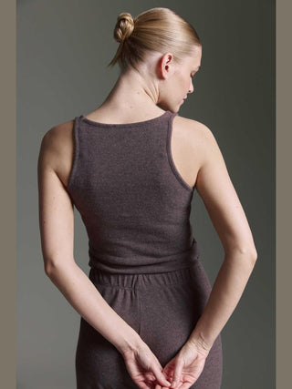 Eine junge Frau trägt das Cotton Candy Roca Top espresso, ein ärmelloses, dunkelgraues Stricktop mit passender, locker sitzender Hose, ihre Haare sind zu einem sauberen Knoten gebunden.
