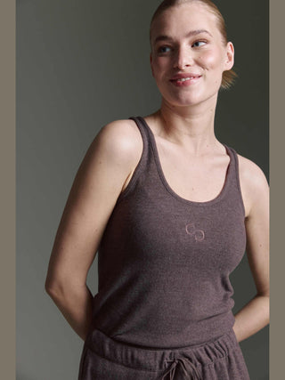 Junge Frau trägt das Cotton Candy Roca Top espresso, ein ärmelloses, scoop-neck Strickoberteil mit kleinem C-Logo, kombiniert mit passenden Strickhosen, in entspanntem und schlichtem Stil.