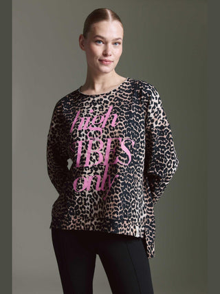 Eine Frau trägt das Cotton Candy Tee Irma multicolor mit lockerem Schnitt und Leopardenmuster, verziert mit dem pinken Slogan „high VIBES only“, vor neutralem Hintergrund.