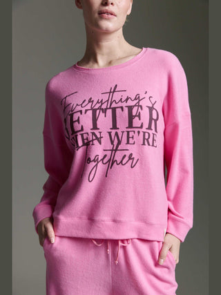 Person trägt Cotton Candy Tee Irma pink mel, ein lockeres Sweatshirt mit Aufschrift „Everything’s BETTER when we’re together“, kombiniert mit passenden pinken Hosen.