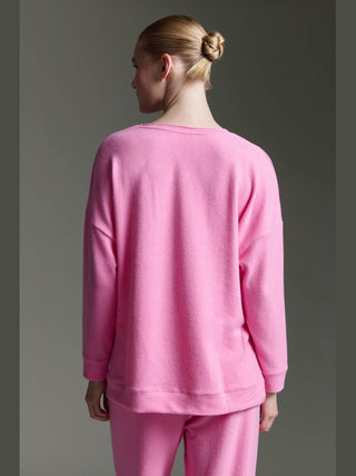 Eine Person trägt das Cotton Candy Tee Irma pink mel, ein locker sitzendes Langarmshirt mit Rollkanten, aus einem weichen Materialmix, sichtbar von hinten mit lässigem Schnitt.