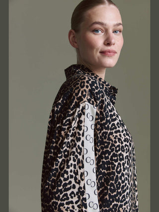 Eine Frau trägt die Cotton Candy Bluse Olivia II multicolor, ein langärmeliges, übergroßes Leopardenmusterhemd mit CS Logo-Streifen an den Ärmeln.