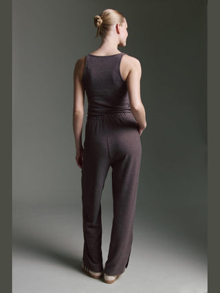 Person von hinten im Cotton Candy Pant Makeda espresso, dunkles ärmelloses Oberteil, weite Loungehose mit elastischem Bund, Hände in Taschen, Haare im Nacken-Dutt.