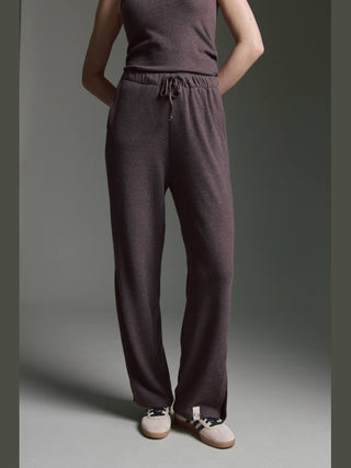 Die Cotton Candy Pant Makeda espresso zeigt sich in dunklem Strickdesign mit einem seitlichen Schlitz am Saum, kombiniert mit einem passenden ärmellosen Oberteil und weißen Sneakern mit schwarzen Schnürsenkeln.