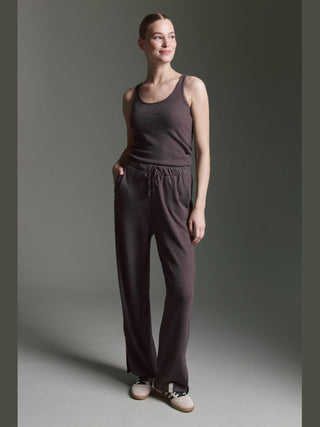 Frau trägt Cotton Candy Pant Makeda espresso, eine weit geschnittene Loungehose mit Kordelzug und seitlichen Taschen, kombiniert mit passendem Tanktop, beide aus weichem Sweatmaterial für Komfort und Stil.