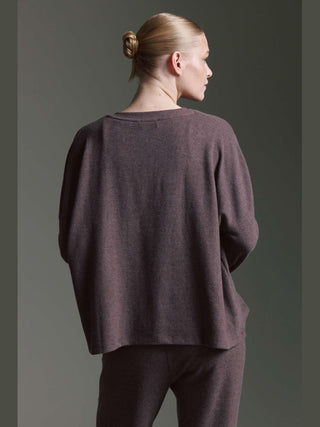 Die Rückansicht zeigt die Cotton Candy Cardigan Odilie espresso, getragen von einer Person mit blonden Haaren im Dutt. Der lockere, langärmlige Schnitt betont den lässigen, fließenden Stil des Cardigans.