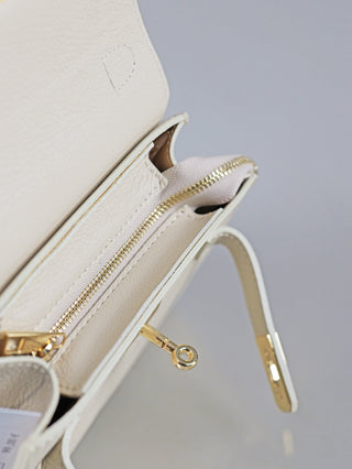 OFF#DLY Leder Bag creme mit geöffnetem Flap zeigt goldene Beschläge, ein Reißverschlussfach mit hellem Fischgrätenmuster und eine kleine Fronttasche.