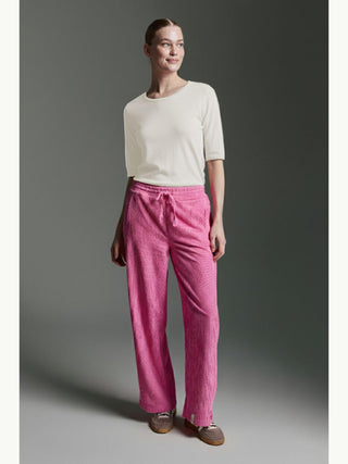 Frau trägt Cotton Candy Tee Bale offwhite, ein schlichtes, halblangärmeliges Oberteil, kombiniert mit pinken Cordhosen und braunen Schnürschuhen, betont durch saubere Linien und lässigen Stil.