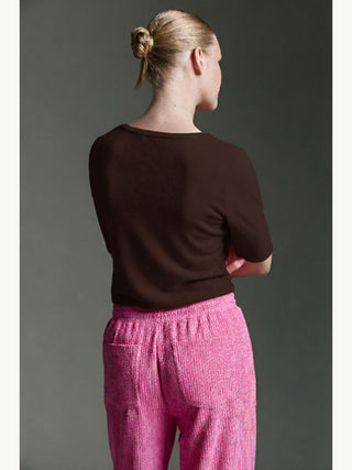 Person von hinten, trägt Cotton Candy Tee Bale espresso mit halblangen Ärmeln. Kombiniert mit auffälligen pinken Hosen, ist das Oberteil ideal für einen stilvollen, vielseitigen Alltagslook.