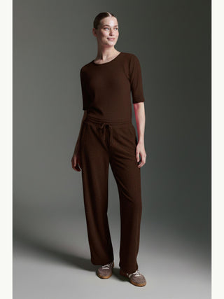 Die Cotton Candy Tee Bale espresso zeigt ein dunkelbraunes, strukturiertes Loungewear-Set mit Rundhals-Pullover und weiten Hosen, kombiniert mit lässigen Schnür-Mokassins.