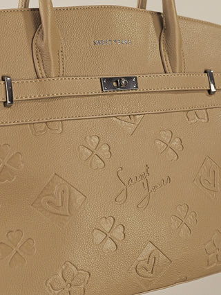 Nahaufnahme der Sweet Years Logo Bag khaki, einer beige/tan Henkeltasche aus genarbtem Leder mit geprägtem Muster aus Kleeblättern, Herzen und „Sweet Years“ Schriftzug. Zwei Griffe und ein drehbarer Metallverschluss.