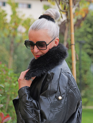 Person trägt die OFF#DLY Jacke Bria black mit Kunstfellkragen und oversized Pilotenstil, ergänzt durch große, dunkle Sonnenbrille. Die Jacke aus Kunstleder verleiht einen markanten, coolen Look.