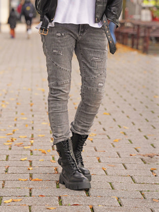 OFF#DLY Destroy Denim Rosella grey: Trägerin auf Kopfsteinpflaster, trägt eng anliegende, leicht zerstörte graue Jeans, kombiniert mit schwarzen Schnürstiefeln und Lederjacke. Perfekter urbaner Streetstyle-Look für den Herbst.