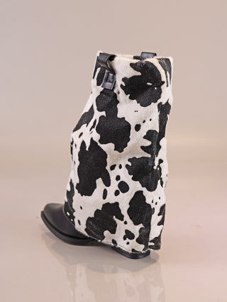 OFF#DLY Cow Boot black/white, ein stylischer Stiefel mit seitlichem Reißverschluss, zeigt ein schwarz-weißes Kuhfell-Muster. Der glatte schwarze Zehenbereich und die Sohle ergänzen das Design.