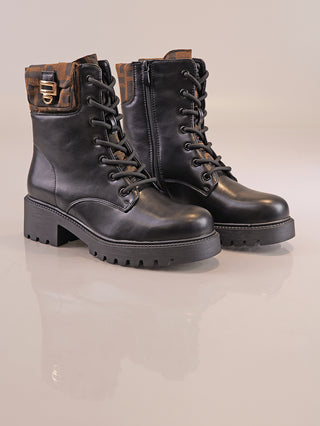 OFF#DLY Boot Zita black: Schwarze Lederstiefeletten mit Schnürung und seitlichem Reißverschluss, dicker Profilsohle, braunen umklappbaren Bündchen mit goldener Schnalle, auf reflektierender Oberfläche präsentiert.