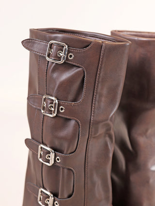 Nahaufnahme des OFF-DLY Biker Boot dark Brown: Kniehohe braune Lederstiefel mit mehreren silbernen Schnallenriemen an der Seite, verdecktem Reißverschluss und einer Plateausohle von 2 cm.