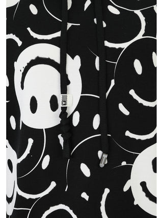 Doris Streich Shirt 349146 schwarz/weiß zeigt einen Hoodie aus elastischer Sweatware mit handgezeichnetem Smiley-Print, schwarzen Kordeln und Metallaglets, das durch seinen einzigartigen Allover-Look besticht.
