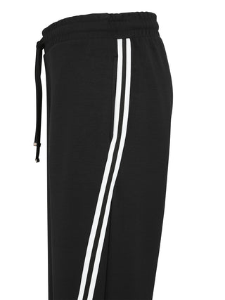 Nahaufnahme der Doris Streich Relax Hose schwarz/weiß: Schwarze Sweatpants mit elastischem Bund und Kordelzug, zwei weißen Streifen seitlich und sichtbarer Seitentasche, betont durch weites Bein und weichen Stoff.