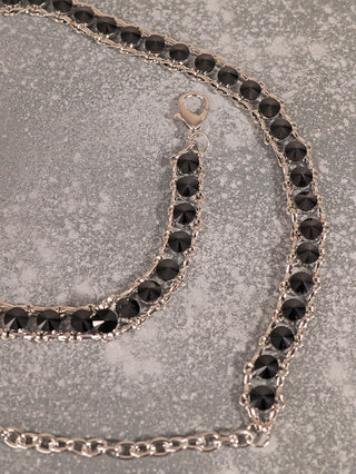 OFF#DLY Kettengürtel silver/black zeigt eine silberfarbene Kette mit facettierten schwarzen Steinen und einem Karabinerverschluss, ideal als verstellbarer Schmuckgürtel. Breite 1,5 cm aus Metall und Glas.