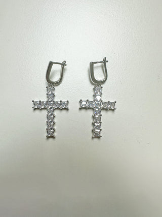 OFF#DLY Ohrschmuck Kreuz silber: Silberfarbene Ohrringe mit kleinen Creolen und einem Kreuzanhänger aus facettierten, klaren Glassteinen in quadratischer Form, eingefasst in einem passenden Metallrahmen.