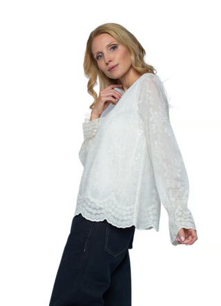 Emily Bluse 157110-10 offwhite/lace: Frau trägt locker sitzende, langärmelige Bluse mit zartem Blumenmuster und Bogenkante. Die Bluse verleiht durch die Volant-Optik an den Ärmeln eine verspielte Note.