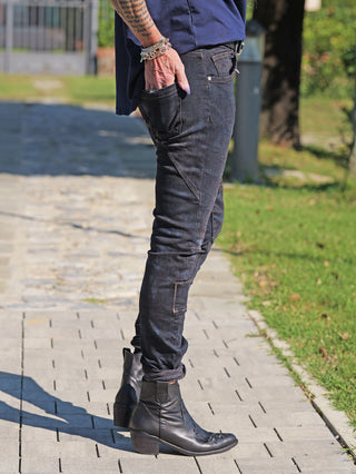 OFF#DLY Denim Karin Dirty Wash: Figurbetonte, dunkle Jeans mit dezenter Used-Optik. Träger steht lässig auf Steinweg, kombiniert mit schwarzen Lederstiefeln und Armbändern.