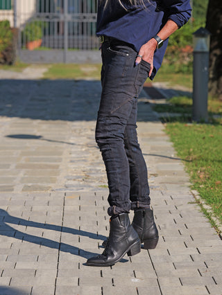 Die OFF#DLY Denim Karin Dirty Wash Jeans zeigt einen figurbetonten Schnitt mit schmalem Beinverlauf, getragen zu schwarzen Lederstiefeletten auf einem Gehweg, betont durch dezente Used-Effekte.