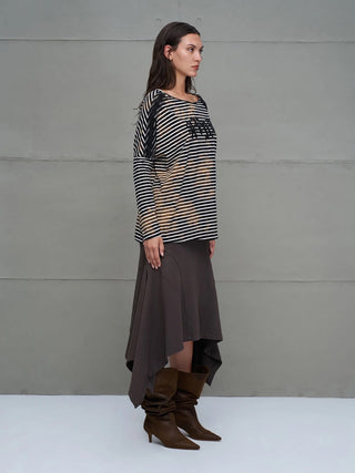 Frau in Profilansicht trägt #VDR T-Shirt 18004 black/white mit schwarz-weißen Streifen, leichtem Bleach-Effekt und glitzerndem Logo, kombiniert mit einem dunklen, asymmetrischen Rock und braunen Stiefeln.