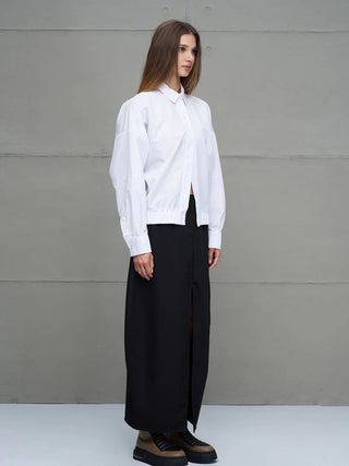 Seitenansicht einer Frau in einem #VDR Shirt 18231 white: oversized, lange Ärmel, elastischer Saum, Not Perfect But Myself-Schriftzug hinten, kombiniert mit schwarzem Rock und zweifarbigen Stiefeln.