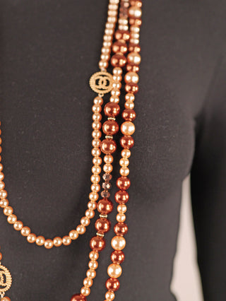 OFF#DLY Kunstperlenkette 3 Strang brown/gold auf schwarzem Büstentorso, zeigt lange, mehrschichtige Ketten aus perlenartigen, bronzenen und champagnerfarbenen Perlen, eine Kette mit kleinem goldenen Medaillon.