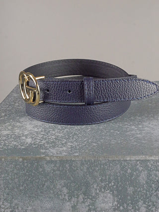 OFF#DLY Ledergürtel CG blue aus navy-texturiertem Leder mit goldfarbener Doppelring-Schnalle und Einzelhalterung, elegant auf grauer Fläche drapiert. Breite: 28mm.