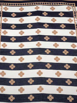 OFF#DLY Schal Britta brown/black mit schwarzen und cremefarbenen Streifen, verziert mit einem sich wiederholenden vierblättrigen Blumenmotiv in Hellbraun, umrahmt von einem geometrischen Diamantmuster. Größe: 180x65 cm.