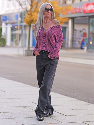 Frau trägt FDL Jeans Brooklyn Black, eine weite, hochgeschnittene Hose. Die Jeans kombiniert Streetstyle mit klassischem Flair, ergänzt durch ein auffälliges pinkes Patch.