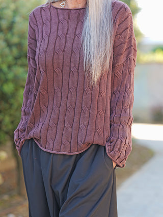 Person trägt den OFF#DLY Pulli Aida schoko, einen locker geschnittenen, strukturierten Feinstrickpullover, mit langen Ärmeln und einem betonten Ausschnitt. Hände in den Taschen einer dunklen Hose.