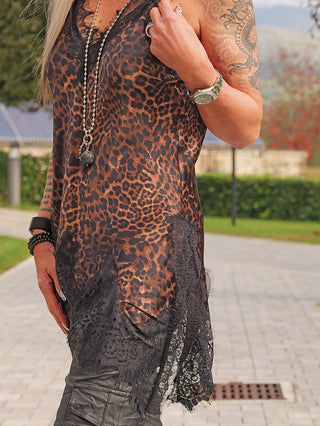 Person trägt das OFF#DLY Top Spitze Leopard, ein ärmelloses, fließendes Leoparden-Print-Top mit schwarzer Spitzenkante, kombiniert mit einer langen Ballkette und mehreren Armbändern.