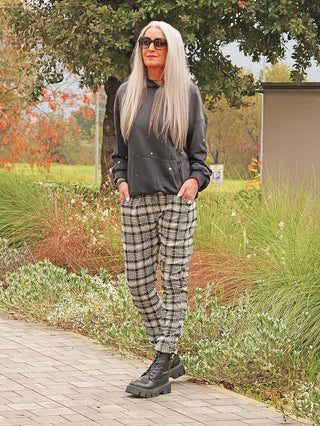 Person trägt den OFF#DLY Hoody Pia black washed mit leicht verwaschenem Look und Stern-Nieten auf Ärmeln, kombiniert mit karierter Hose und klobigen Boots.