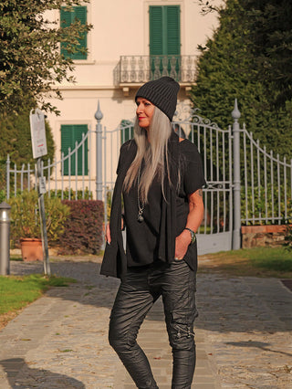 Eine Frau trägt den OFF#DLY Pulli m. Schal Carla black, ein lockeres, modernes Strickset mit passendem Schal, ideal für lässige Herbststyles, während sie vor einem eleganten Villaeingang steht.