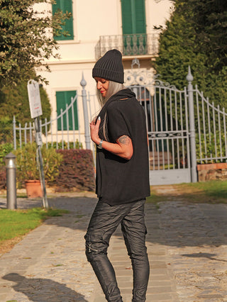 Eine Person trägt den OFF#DLY Pulli m. Schal Carla black, ein lockeres, modernes Strick-Set mit passendem Schal, perfekt für lässige, stilvolle Herbst-/Winter-Looks, während sie im Garten spaziert.