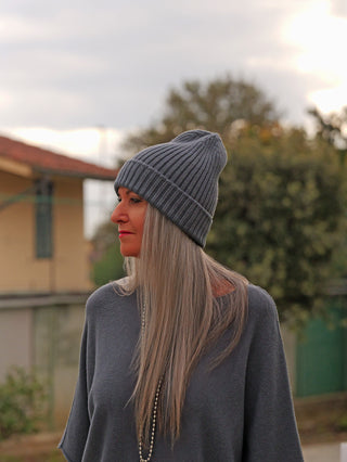 Person mit langem Haar trägt die OFF#DLY Mütze Anna asphalt, eine gerippte graue Strickmütze. Sie steht im Profil, bekleidet mit einem locker sitzenden grauen Oberteil.