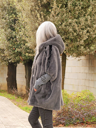 Person von hinten, trägt die OFF#DLY FakeFur Jacke Rom asphalt mit Kapuze, aus weichem Kunstpelz, über dunklen Hosen. Der Schnitt ist leger und leicht oversize.