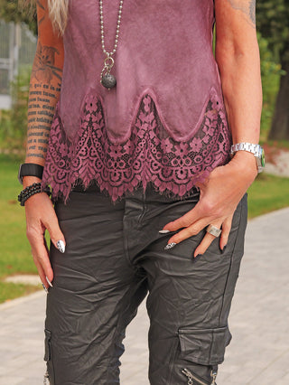 Person trägt das OFF#DLY Top Spitze Allegra plum mit floraler Spitzenkante und verstellbaren Trägern, kombiniert mit schwarzen Cargo-Hosen, Accessoires und auffälligem Nageldesign.